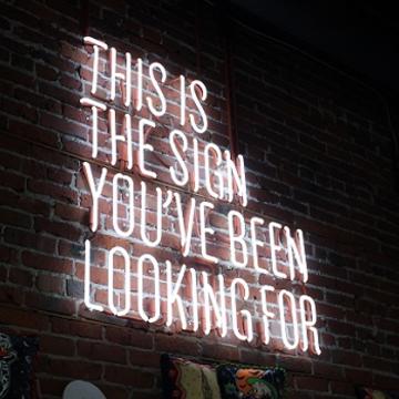 This is the sign you have been looking for by Austin Chan on Unsplash Image depicts the following sentence in capital letters as a neon light display mounted on an brick wall: This is the sign you have been looking for