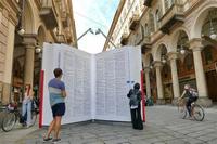 People looking at a giant book in the middle of a street