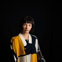 Life like robot of a woman wearing shirt of white, black and mustard colouring